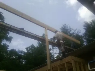 Carpenter setting a ridge beam over a new addition frame — Ice Dam Removal by Roofing Brothers in Port Haywood