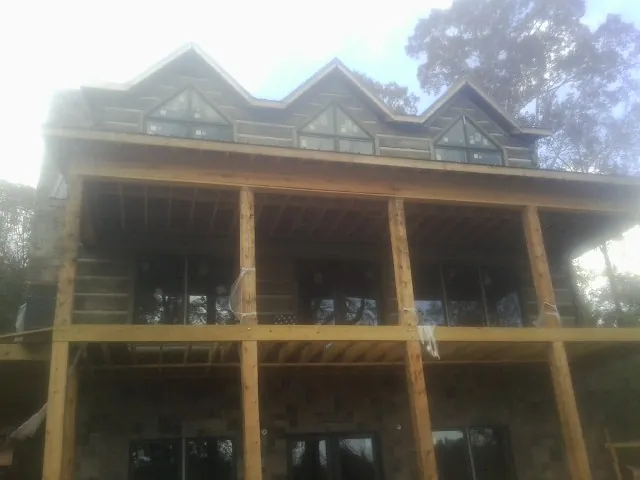 Dormers and porch framing on a large log home under construction — Roof Coating work by our crew in Port Haywood