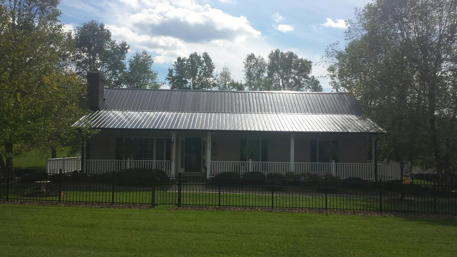 Gray metal roof on a brick ranch with a full width front porch — Gutter Guard Installation work by our crew in Port Haywood