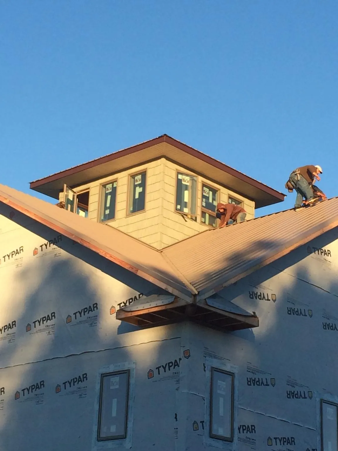 Roofers working around a rooftop cupola on a new metal roof at sunset — Roof Waterproofing in Port Haywood by Roofing Brothers